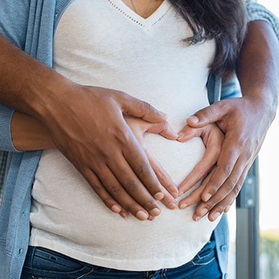 man and woman holding pregnant woman's stomach